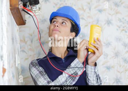 female electrician using multimeter on old electric meter Stock Photo