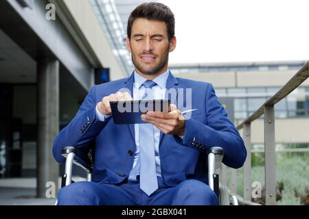 disabled businessman on wheelchair checking tablet Stock Photo