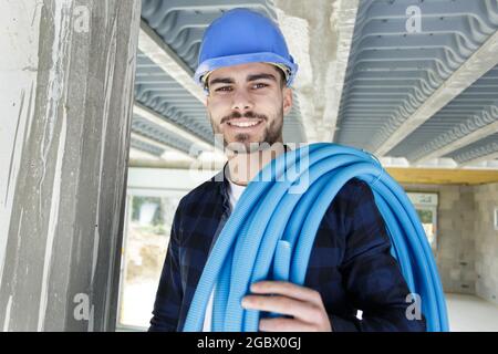 plumber with a reel of flexible blue pipe Stock Photo