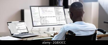 African American In Wheelchair Using Computer. Handicapped Developer Coder Stock Photo