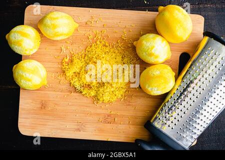 Lemon Zest on a Bamboo Cutting Board: Zested lemons and a box grater on a wood cutting board Stock Photo