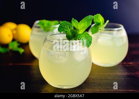 Glasses Limonata Turkish Lemonade with a Mint Garnish: Lemonade with a mint garnish on a wooden table Stock Photo