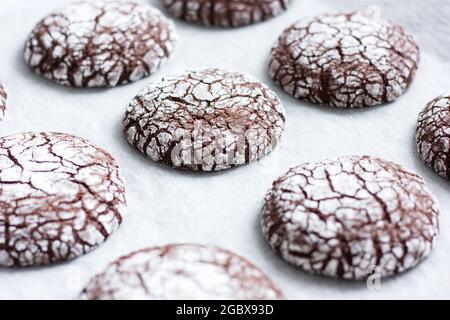 Batch of chocolate crinkle cookies on a parchment paper. Stock Photo