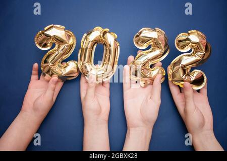 2022 year gold balloons on ribbons with confetti on pink wall. Happy New year 2022 eve