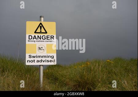 Danger strong inshore currents swimming not advised sign with icons. Authentic, on beach path. No people. Stock Photo