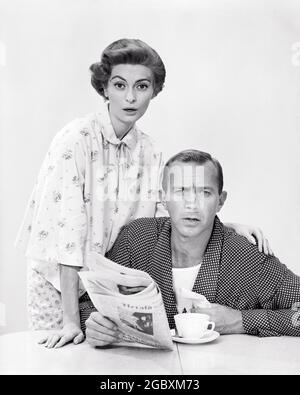 1960s HUSBAND WIFE WEARING PAJAMAS BREAKFAST TABLE WOMAN BEHIND MAN HOLDING NEWSPAPER BOTH SERIOUS EXPRESSIONS LOOKING AT CAMERA - s5899 CRR001 HARS SPOUSE HUSBANDS HOME LIFE COPY SPACE FRIENDSHIP HALF-LENGTH LADIES PERSONS THOUGHTFUL MALES NEWSPAPERS PAJAMAS EXPRESSIONS B&W MORNING PARTNER WIDE EYE CONTACT SPOUSES BUG-EYED BEVERAGE DISCOVERY FLUID SINCERE CAFFEINE JOE NEWSPRINT SOLEMN WIDE-EYED COOPERATION FOCUSED INTENSE JAVA MID-ADULT MID-ADULT MAN MID-ADULT WOMAN STARTLED TOGETHERNESS WIVES BEVERAGES BLACK AND WHITE CAREFUL CAUCASIAN ETHNICITY EARNEST INTENT OLD FASHIONED Stock Photo