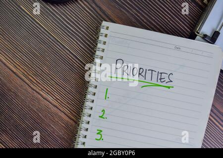 Priorities write on a book isolated on Wooden Table. Stock Photo