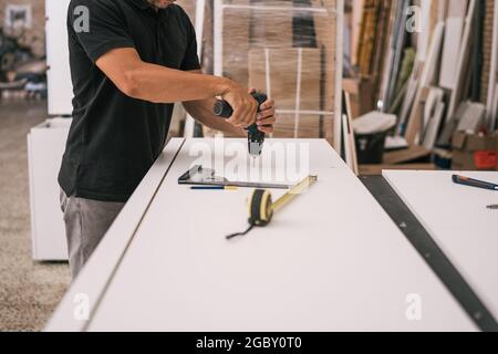Man using an electric drill in a surface in a workshop Stock Photo