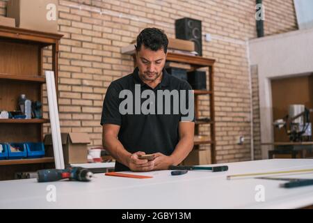 Man using a smartphone in a workshop Stock Photo