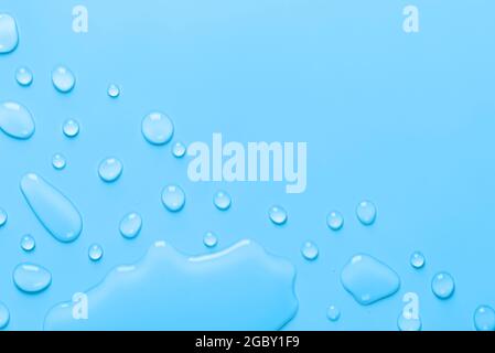 Splash of Water and drops on a pastel blue background. Water texture close up. Backdrop glass covered with drops of water. Water bubbles. Stock Photo