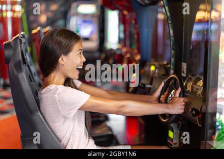 Arcade game machine adult woman having fun playing racing car videogame driving virtual sports cars Stock Photo