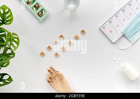 Text Long Covid, wooden letters. Hand with weekly planner, calendar with all days crossed out. Cancellation, change of plans due to chronic covid Stock Photo