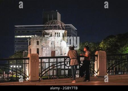 Hiroshima, Japan. 05th Aug, 2021. People look at the Atomic Bomb Dome that lights up at night. This Friday will mark the 76th anniversary of the atomic bombing of Hiroshima, which killed about 150,000 people and destroyed the entire city for the first bombing with a nuclear weapon in war. Limited guests and Japan's dignitaries including Prime Minister Yoshihide Suga will attend the Peace Memorial Ceremony amid the coronavirus pandemic. Credit: SOPA Images Limited/Alamy Live News Stock Photo