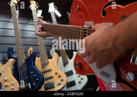 Berlin, Germany. 05th Aug, 2021. A man plays a left-handed guitar in a guitar shop. Credit: Paul Zinken/dpa/Alamy Live News Stock Photo