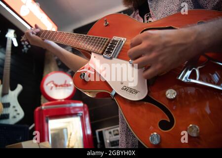Berlin, Germany. 05th Aug, 2021. A man plays a left-handed guitar in a guitar shop. Credit: Paul Zinken/dpa/Alamy Live News Stock Photo
