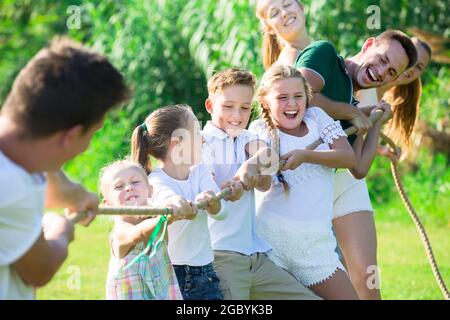 Joyful kids with parents playing tug of war Stock Photo