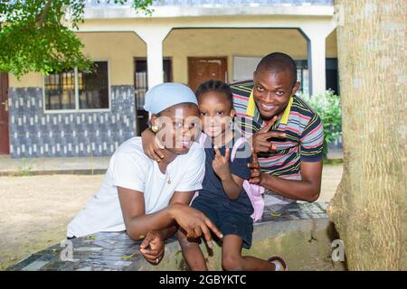 African mother and father or guardian sitting together with their daughter in a school environment, available to help the girl child attain excellence Stock Photo