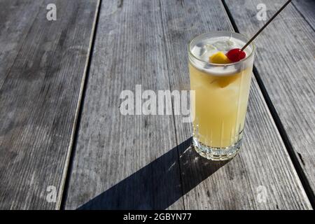 A hand holding a Whisky cocktail made with orange served at an outdoor bar in Bodega Bay, California Stock Photo