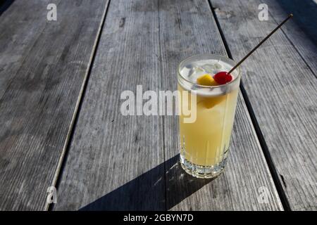 A hand holding a Whisky cocktail made with orange served at an outdoor bar in Bodega Bay, California Stock Photo