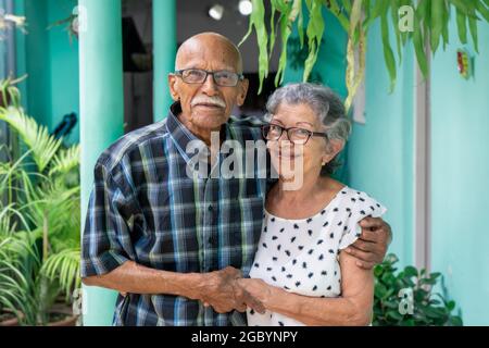 Elderly couple embracing and smiling looking at the camera Stock Photo