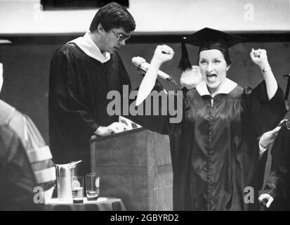 College Station Texas USA, 1978: Female graduate wearing a cap and gown reacts with elation while crossing the stage during  Texas A&M University's commencement ceremony.  ©Bob Daemmrich Stock Photo