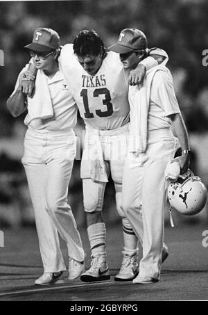 Austin Texas USA, circa 1986: Injured Texas football player leaves the field of play with the help of team athletic trainers. ©Bob Daemmrich Stock Photo