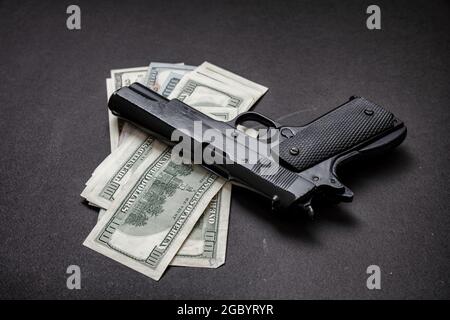 Crime concept, pistol handgun 9 mm and American dollar banknotes on black background. Criminal money, mafia and corruption concept, Stock Photo