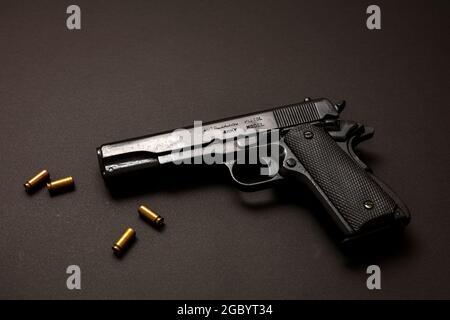 Pistol gun 9mm and ammo bullets on black background. Black metal weapon, automatic handgun for military and security on a vintage table. Side view Stock Photo