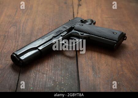 Pistol 9mm on wooden background. Black metal gun weapon, automatic handgun for military and security on a vintage table. Side view Stock Photo