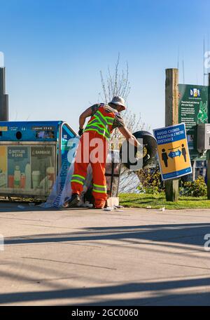 Garbage removal man in uniform working for a public utility emptying trash bins on a street of a Richmond area, BC, Canada-April 18,2021. Stock Photo