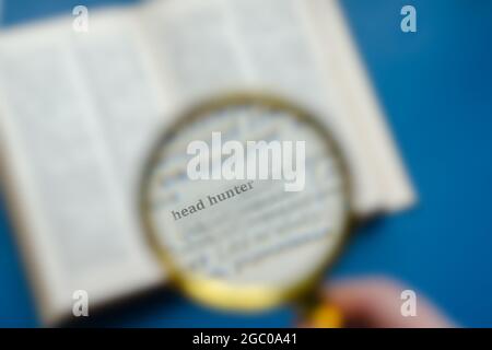 Word Headhunter focuses on a magnifying glass. Education, foreign language learning, search for knowledge concept. Defocus, blur, noise effect Stock Photo