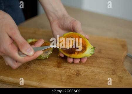 Female eats fresh organic ripe cactus pear or opuntia with a spoon. Exotic fruits, healthy eating concept Stock Photo