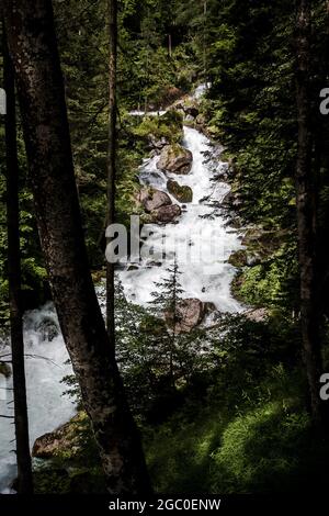 Vertical shot of the Waldbach waterfall in Austria surrounded by lush trees and greenery in a forest Stock Photo