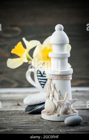 Vintage background with blue heart coffee cup and white lighthouse on wooden table. Toned image Stock Photo