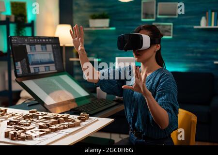 Modern business woman with vr glasses for innovation development vision using interactive software. Virtual designer working on holographic simulation experience for building model Stock Photo