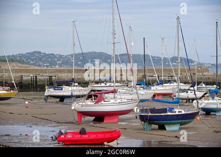 BRAY, IRELAND - Jun 19, 2021: Multiple yachts at Bray Harbour at low tide in Bray, County Wicklow, Ireland. Sailing boats resting on their keels. Clou Stock Photo