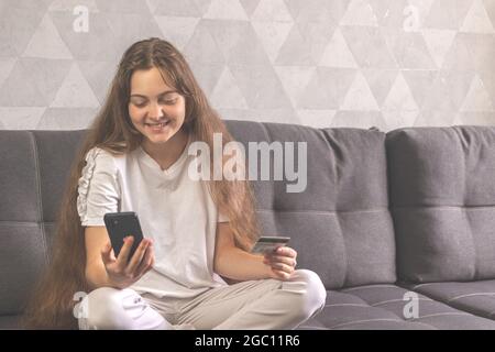 Woman paying with credit card online while making orders via mobile phone making transaction with mobile bank applications Stock Photo