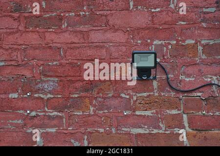 Light with automatic motion sensor on a red brick wall. Stock Photo