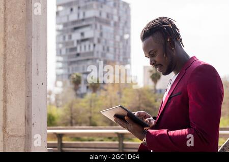 black businessman using a tablet outdoors in the city, technology and remote work concept, copy space for text Stock Photo