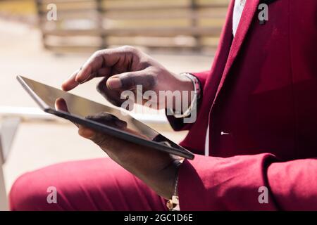 detail of the hands of an african man using a tablet outdoors in the city, technology and remote work concept Stock Photo