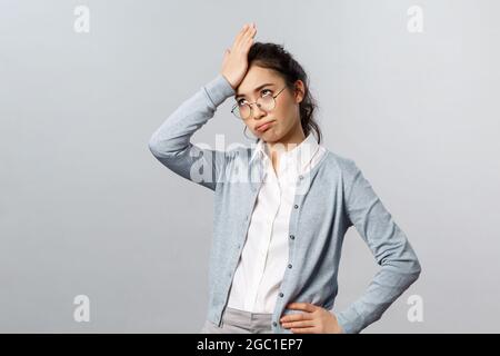 Oh my god, so lame. Tired and annoyed asian woman, teacher having troubles with online education app, punch forehead, facepalm sighing heavily and Stock Photo