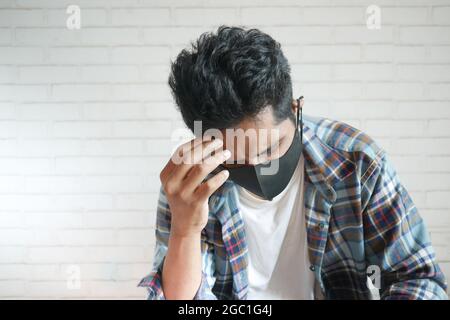young sick man with face mask suffering headache  Stock Photo