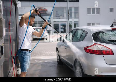 Process of man washing his car in a self-service car wash station Stock Photo