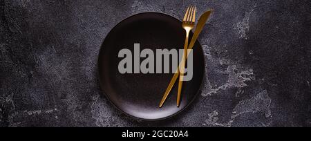 Clean empty black plate with cutlery. Copy space, mock up, top view. Concept for menu with utensil. Stock Photo