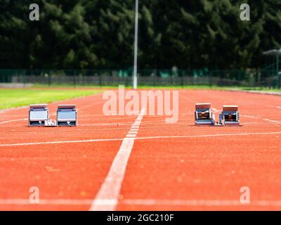 Starting blocks on light red running tracks lanes at track and field stadium. Sport accessory. Stock Photo