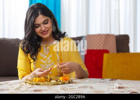 A HAPPY YOUNG WOMAN SITTING AND HOLDING RAKHI Stock Photo