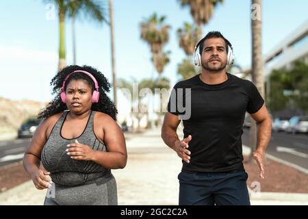 Personal trainer doing running exercises with afro curvy woman - Sporty people lifestyle concept Stock Photo