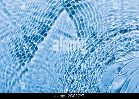 Defocused blue transparent water surface texture with waves and ripples. Abstract background. Stock Photo