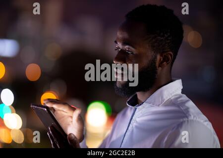 African american businessman working at night using smartphone Stock Photo