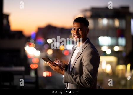 Portrait of mixed race businessman working at night using tablet Stock Photo